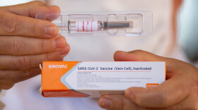 A professor at the University of Brasilia and coordinating doctor for tests of the Sinovac Biotech vaccine, shows the vaccine to journalists amidst the coronavirus pandemic on Aug. 5, 2020 in Brazil. (Andressa Anholete/Getty Images)