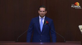 House Speaker Daniel Perez smiles behind a podium 