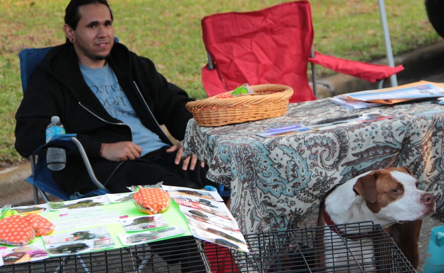 CEASAR -- Bryant Silva, 28, of Hollywood, FL, and a rescue dog named Ceasar sit underneath the tent for Second Chance, a rescue and rehoming organization for dogs on Saturday, April 2, 2016. (Photo by Samuel Figuera)