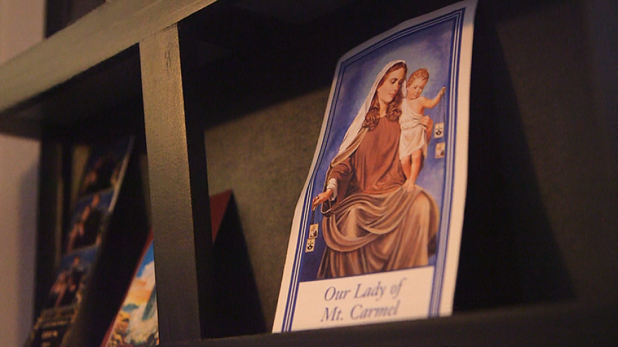 An illustrated card of Our Lady of Mt. Carmel is placed on a shelf.