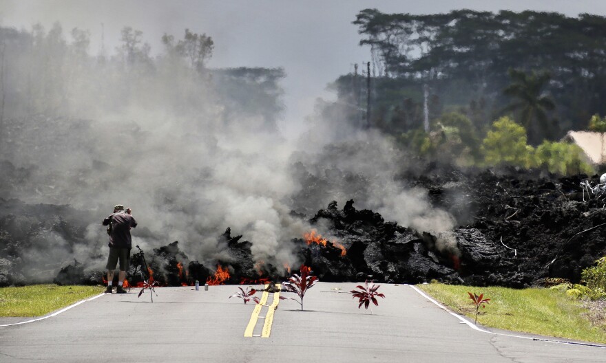 FILE - In this May 5, 2018 photo, a man photographs lava from Kīlauea volcano as it flows through the Leilani Estates subdivision near Pāhoa, Hawaiʻi.