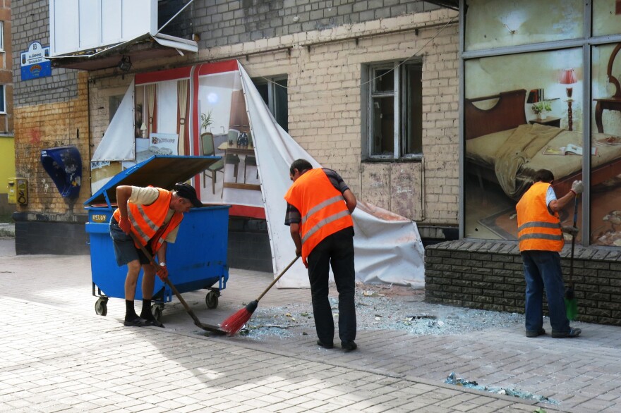 Street sweepers clean up broken glass and debris after a Ukrainian army artillery attack in late August on Russian-backed separatist fighters in Donetsk. One street sweeper was killed in late July by shelling — but the need for a paycheck and the pride they take in their city is what keeps city government workers like these returning to work each day.