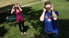 Alex Potess, left, and Kate Howell view the 2017 partial eclipse of the sun from Butler Park in downtown Austin.