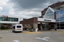 The main entrance of Carle BroMenn Medical Center showing a small passenger van parked outside and an enclosed walkway above adorned with a logo that reads 'Carle.'