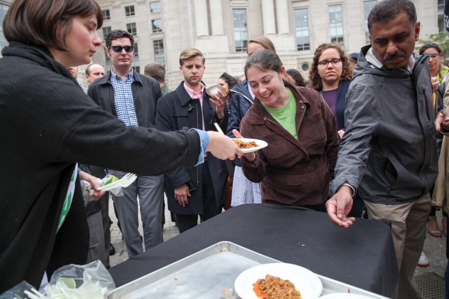 A volunteer hands out plates of paella.