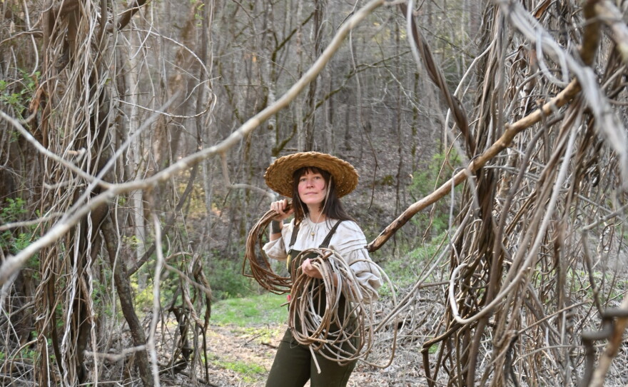 A woman is surrounded by kudzu vines in the woods.