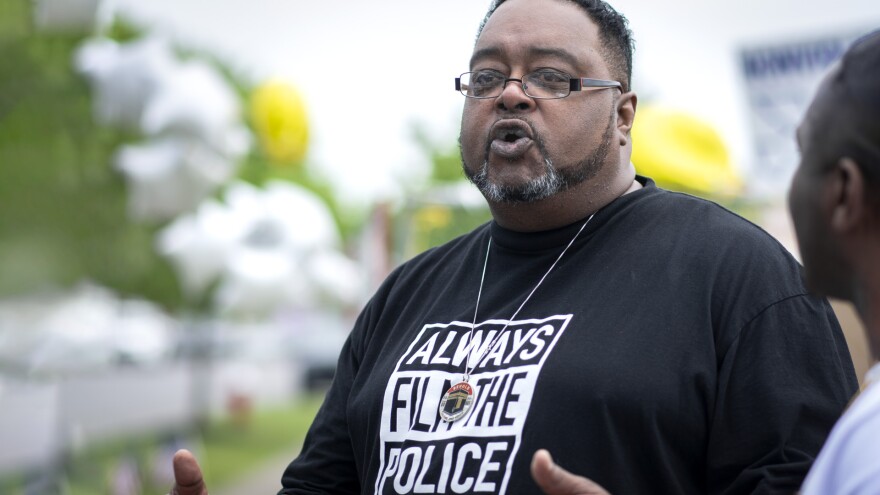 A man wearing a black and white "ALWAYS FILM THE POLICE" t-shirt.