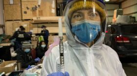 Dr. Shana Theobold holds up a dose of the COVID-19 vaccine.