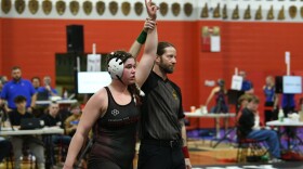 A referee raises Madison Beauregard's left arm over her head to indicate she's won a match.