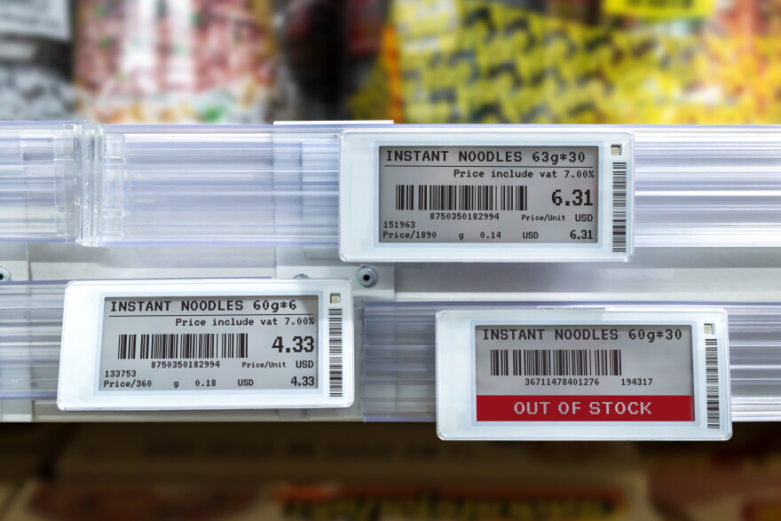 Three digital price tags for instant noodles show prices for two items and that a third is out of stock.