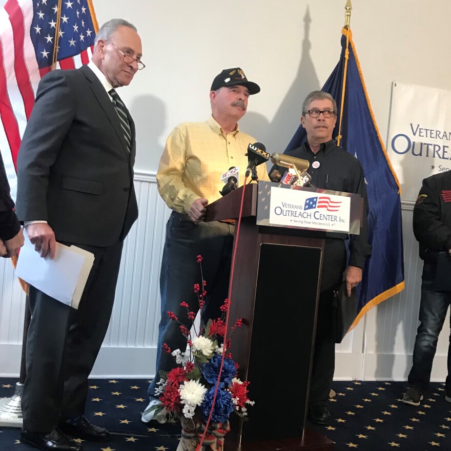 Senator Chuck Schumer stands to the left of veterans James Myers and Manuel Silva as they give their statements to the crowd.