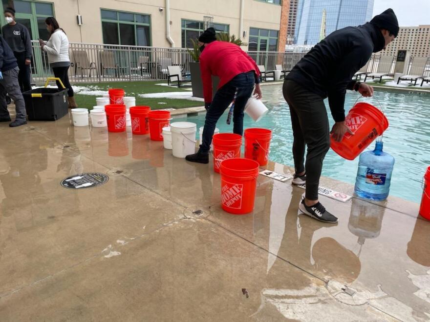 Residents of The Inspire fill buckets with pool water.