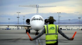 In this Thursday, May 9, 2013, photo, an airline ground worker guides an incoming Allegiant Air jetliner at McCarran International Airport, in Las Vegas. While other U.S. airlines have struggled with the ups and downs of the economy and oil prices, tiny Allegiant Air has been profitable for 10 straight years. (AP Photo/David Becker)