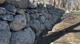 A stone wall on the edge of a feild