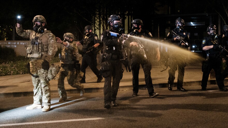 Federal officers use tear gas and other crowd dispersal munitions on protesters outside the Multnomah County Justice Center on Friday in Portland, Ore.
