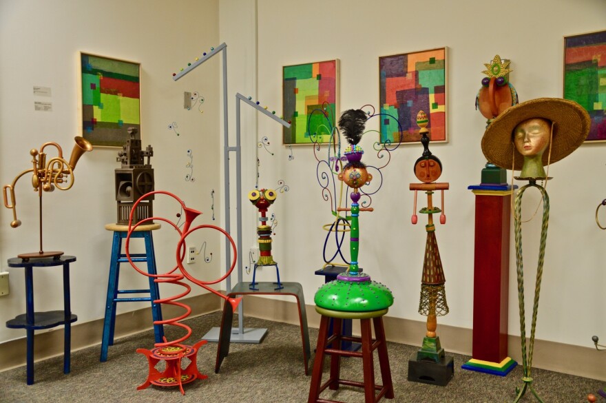 A colorful art display made of various objects, like old musical instruments and chimney brushes.