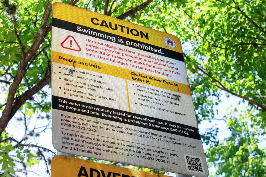 A caution sign prohibiting swimming from the city of Austin by Lou Neff point on Lady Bird Lake on Thursday, July 17, 2025. Leila Saidane/KUT News