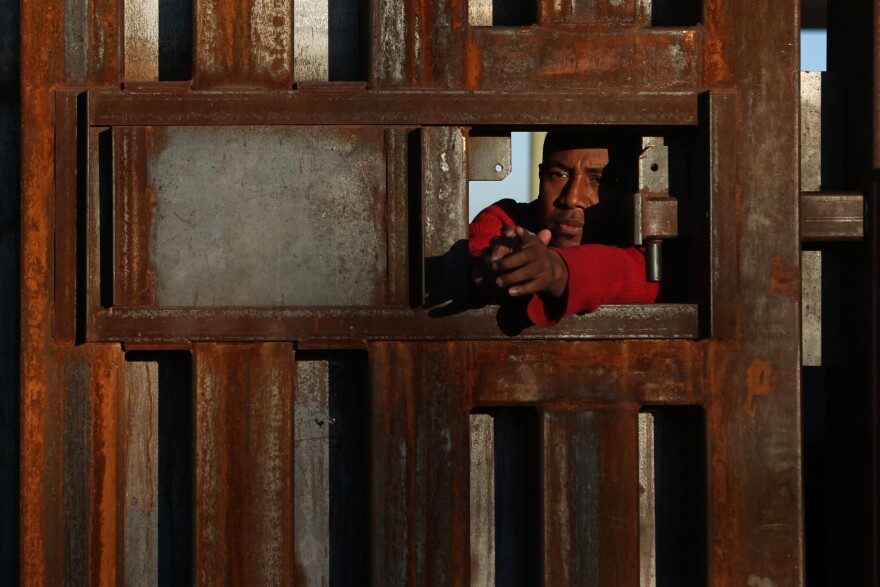 Asylum-seeking migrants wait at the border wall to be processed by U.S. Customs and Border Protection after crossing the Rio Grande River into the United States in El Paso, Texas, U.S., December 21, 2022.