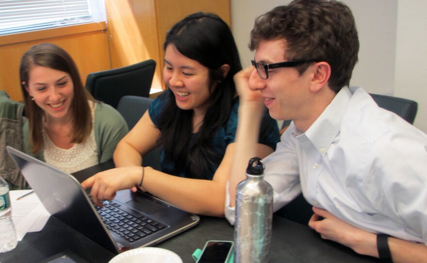 (Left to right) Students Christine Schindler, Mary Quien and Micah Timen share popcorn and a laugh during a research session. Timen worked as an accountant before medical school; his database project tracked the relative costs of a hip replacement throughout New York compared to the relative costs of a fast-food hamburger.