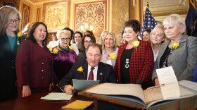 Utah Gov. Gary Herbert signs bill honoring the state's pioneering women suffragists on Wednesday. He's surrounded by state senators and representatives, and his wife, who are all wearing the yellow rose symbolizing suffrage.<em> </em>
