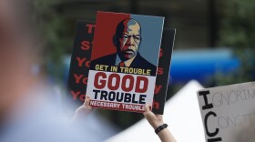A protester holds a sign featuring former Congressman John Lewis as people rally in Daley Plaza as part of the "Good Trouble Lives On" national day of action, in Chicago, Thursday, July 17, 2025. (AP Photo/Erin Hooley)