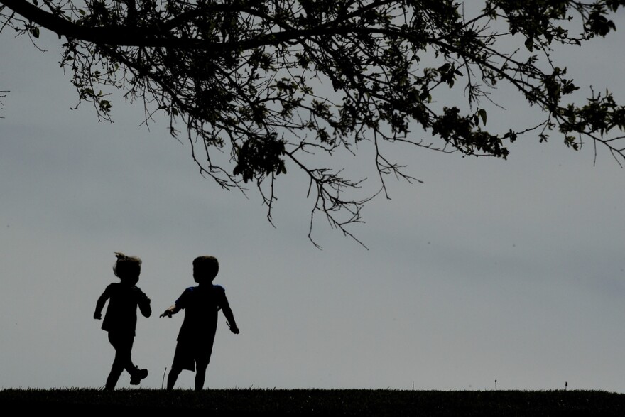 Children run on the lawn at the Liberty Memorial in Kansas City, Mo., on April 28, 2020. (AP Photo/Charlie Riedel, File)