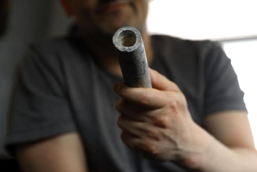 Troy Hernandez, an environmental justice activist with Pilsen Environmental Rights and Reform Organization shows a piece of lead pipe obtained from his residence during his home renovation, Friday, April 9, 2021 in Chicago's Pilsen neighborhood. Hernandez recently spent $15,000 to replace the lead service lines bringing water into his home. (Shafkat Anowar/AP)