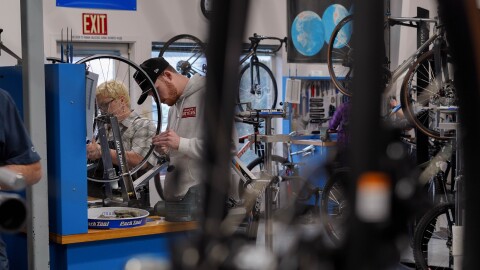 Students work on bike wheels in a classroom.