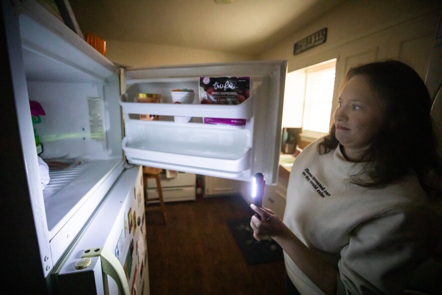 Stef Schrader uses a flashlight to peek in her freezer, where salmon and dumplings have thawed out after two days without power. 