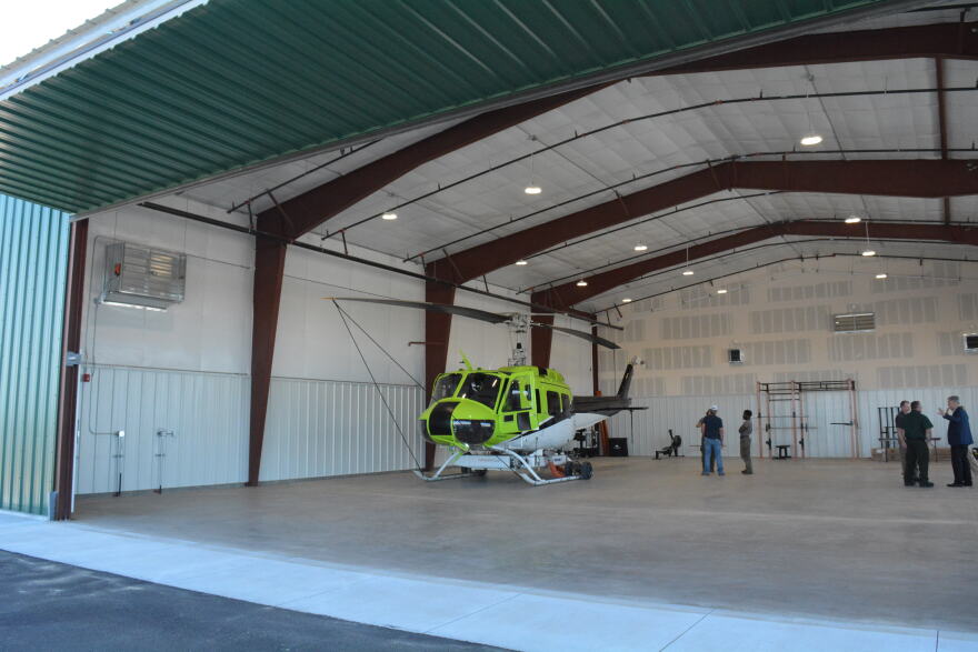 A lime green and white helicopter sits in a hangar.