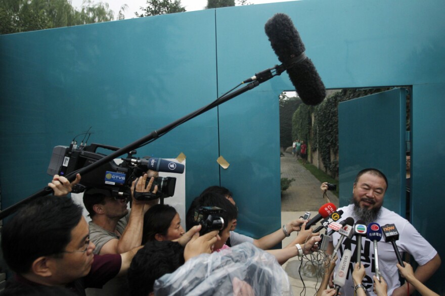 Activist artist Ai Weiwei speaks to journalists gathered outside his home in Beijing, China, Thursday.