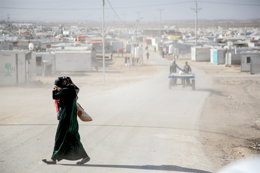 A mother shields her child from the dust in Jordan's Zaatari Camp for Syrian refugees.