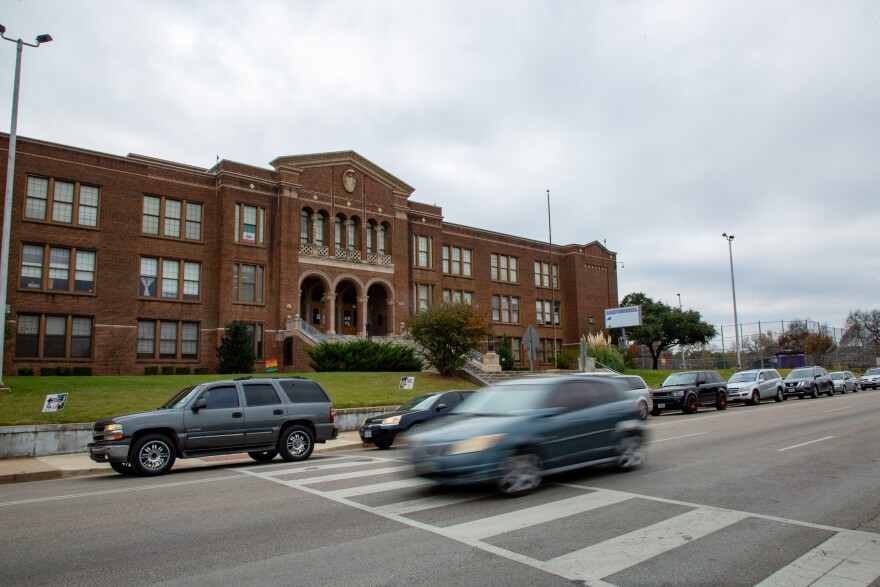 A car speeds by as others wait in line for a food giveaway hosted by Dallas ISD, on Nov. 12, 2020.