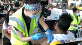 A resident receiving her first shot at the M&T Bank Stadium. The city is shifting away from mass vaccination sites to focus on mobile clinics. Credit: Sarah Y. Kim/WYPR