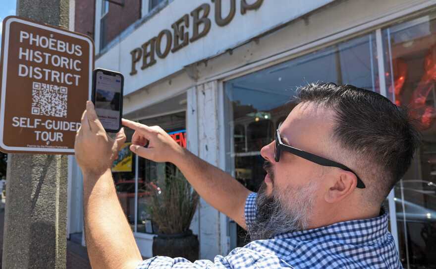 Neighborhood Commissioner Joe Griffith demonstrates how to try out the Phoebus self-guided walking tour using new signs around the neighborhood on Thursday, May 30, 2024.