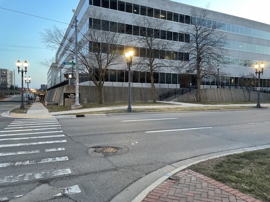 Ottawa Street, with a crosswalk and three car lanes and state offices in the background.