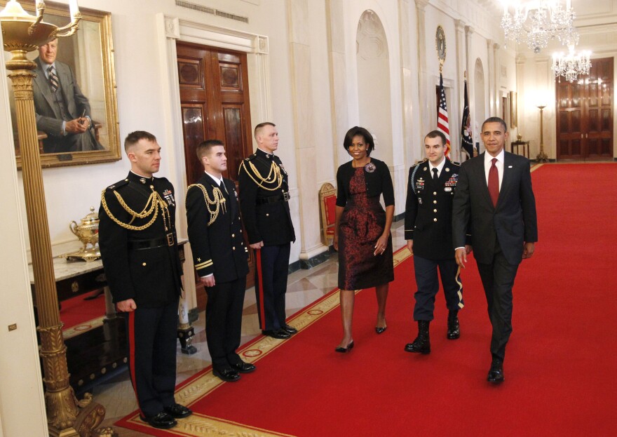 President Barack Obama and first lady Michelle Obama walk down the Cross Hall of the White House in Washington, Tuesday, Nov. 16, 2010, with Army Staff Sgt. Salvatore Giunta, before presenting him with the Medal of Honor during a ceremony in the East Room . Giunta, from Hiawatha, Iowa, is the first living veteran of the wars in Iraq and Afghanistan to receive the award.