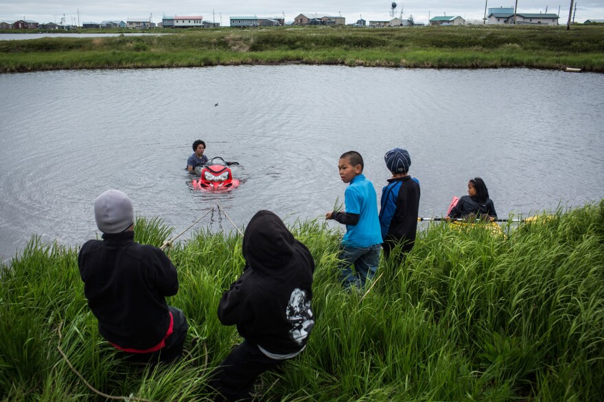 Yup'ik children help recover a snowmobile that sank when its owner attempted to drive across a pond, on June 30, 2015, in Newtok.