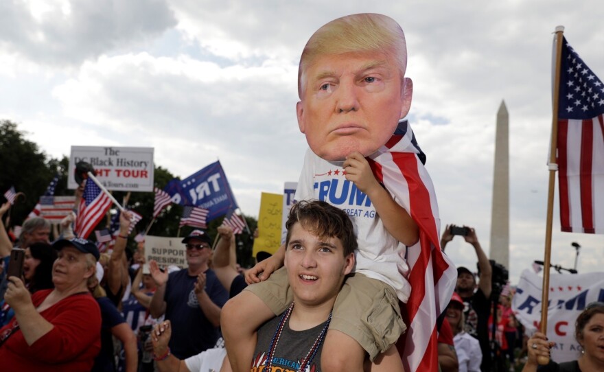 Gabriel Gunstin of Southern Township, Michigan, holds up his nephew, James Crockett, 9, with a Trump mask at the 'Mother of All Rallies.'