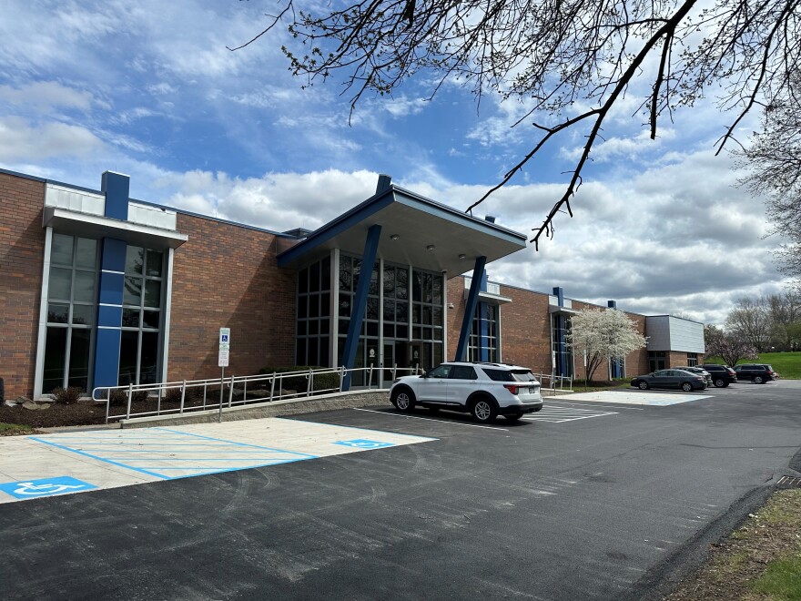 A building with large glass windows sits against a partly cloudy sky.
