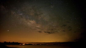 A starry night sky over a body of water.