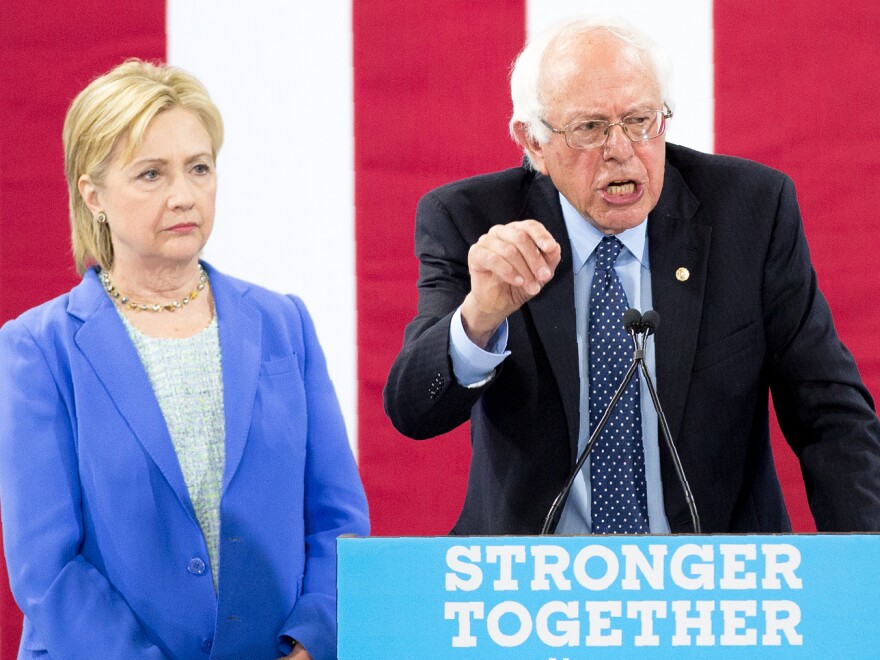 Hillary Clinton listens as Bernie Sanders makes remarks during a unity rally in July 2016 in New Hampshire.