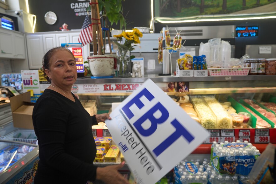 El Recuerdo Market manager Cecilia Benitez sets up a "EBT (Electronic Benefit Transfer) Accepted Here," banner in Los Angeles, Friday, Oct. 31, 2025, after two federal judges ordered President Donald Trump's administration to continue funding SNAP during the government shutdown. (AP Photo/Damian Dovarganes)