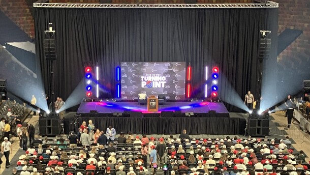 A stage is set up in front of rows of chairs. The logo behind the stage reads "This is the Turning Point tour."