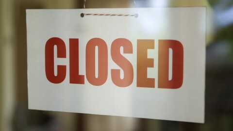 Closed sign board hanging on the glass door of cafe or small store