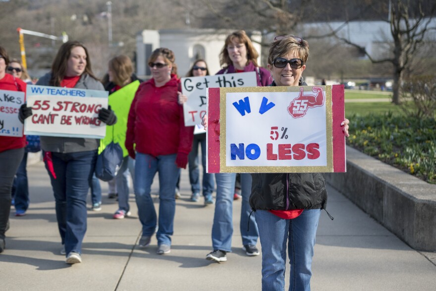 Elizabeth Ferguson Hollifield, a teacher from Princeton W.Va., holds a sign as she walks to a teacher rally Monday, March 5, 2018.