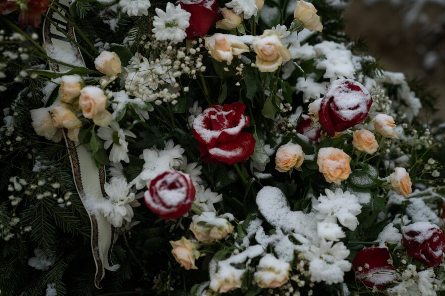 Atop the freshly dug graves at the Lychakiv cemetery there are piles of flowers, with a slight dusting of snow lingering on the petals.