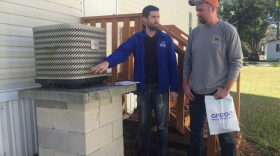 Michael McCabe (left) teaching Joshua Pettit (right) about ways to keep his air conditioning unit clean. He explains to Pettit that his unit is only five to six years old and should be fine. McCabe is also collecting information on the unit to make sure that it matches the air handler inside. (Sydney Martin/ WUFT News)
