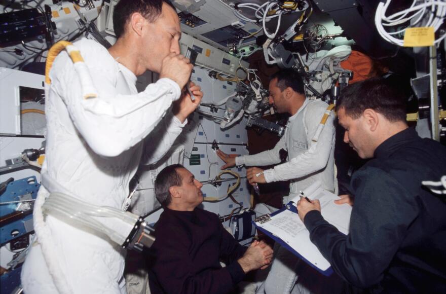 Astronauts James H. Newman (left) and Michael J. Massimino wear the liquid cooling and ventilation garment that complements the spacesuit during a 2002 mission. Also pictured on the Columbia space shuttle are pictured are astronauts John M. Grunsfeld (right) and Richard M. Linnehan.