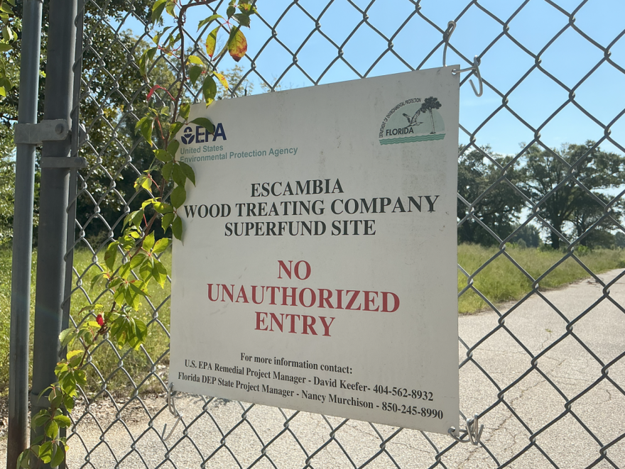A sign marks the Escambia Wood Treating Company Superfund site, warning against unauthorized entry. The site, which is fenced and closed to the public, is the focus of ongoing environmental cleanup efforts.
